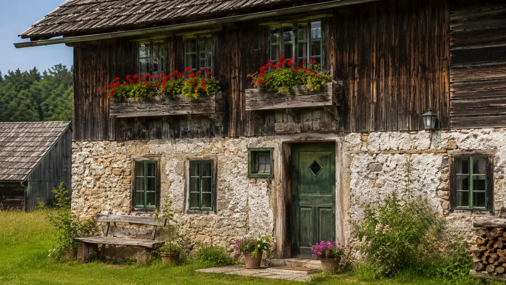 rustikale bauernhofszene mit altem sacherl holzfassade steinmauer blumen und gruenem naturraum